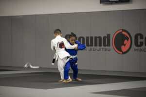A young Jiu-Jitsu student training with a coach during a youth class.