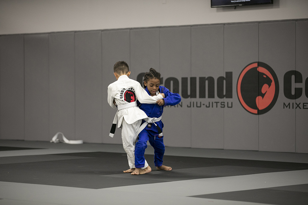 A young Jiu-Jitsu student training with a coach during a youth class.